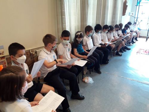 Grupo de alumnos sentados en el oratorio con su libro de oraciones de la mano